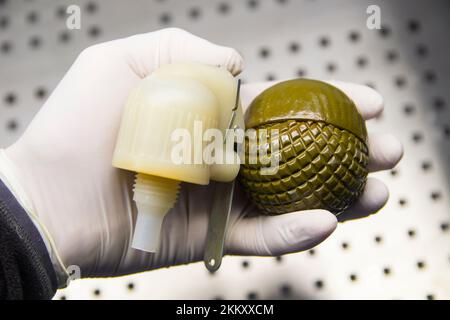 Die Hand eines Mannes in einem Gummihandschuh hält eine zerlegte Granate Nahaufnahme Stockfoto