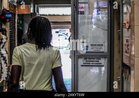 Eine Frau geht an einer Restauranttür vorbei, geklebt mit einer alten Covid-19-Warnung mit dem Aufdruck "kein Zutritt für vermutete Covid-19-Fälle" in einer Mall in Nakuru. Kenias Covid-19-Übertragungsrate ist niedrig geblieben, obwohl die Fälle in China immer mehr zunahmen, was Lockdowns erforderlich machte. (Foto: James Wakibia / SOPA Images/Sipa USA) Stockfoto