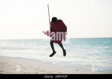 Sansibar, Tansania - 2. Januar 2022: Maasai-Krieger in traditioneller Kleidung am Sandstrand der Insel Sansibar. Stockfoto