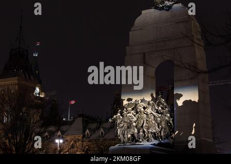 Das National war Memorial of Canada ist schneebedeckt und beleuchtet bei Nacht, der Parliament Hill ist im Hintergrund zu sehen. Stockfoto