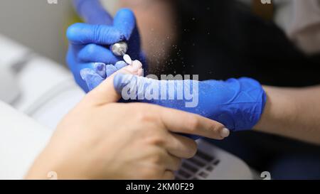 Maniküre, die mit Spezialwerkzeugen bei einer Klientin eine Hardware-Maniküre macht Stockfoto