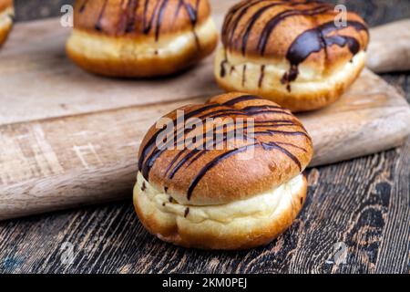 Köstlicher Donut bedeckt mit Schokoladenlinien und einer Füllung mit milchweicher Schokolade, ein Donut mit Schokoladenfüllung und in Schokolade Stockfoto