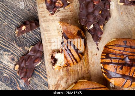Köstlicher Donut bedeckt mit Schokoladenlinien und einer Füllung mit milchweicher Schokolade, ein Donut mit Schokoladenfüllung und in Schokolade Stockfoto