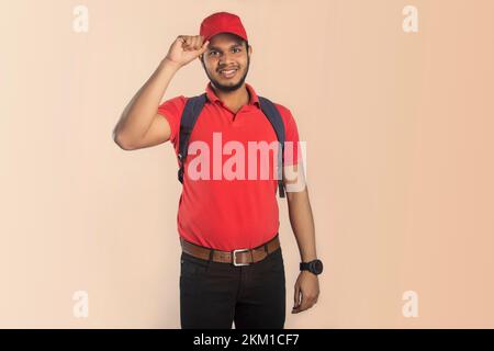 Porträt eines selbstbewussten jungen Auslieferers, der die Mütze hält Stockfoto