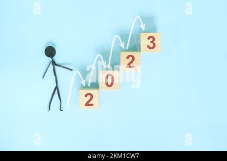 Erfolgsleiter für das neue Jahr 2023, positive Aussichten und Konzept für schrittweises oder schrittweises Wachstum. Holzblöcke mit blauem Hintergrund. Stockfoto