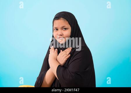 Mädchen trägt traditionellen islamischen Hijab Schal, Hände auf der Brust und schaut in die Kamera Stockfoto