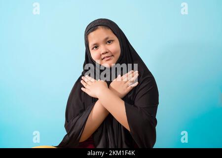 Mädchen trägt traditionellen islamischen Hijab Schal, Hände auf der Brust und schaut in die Kamera Stockfoto