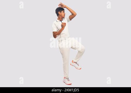 Ein Junge liefert einen Spin Ball während eines Cricket-Spiels Stockfoto