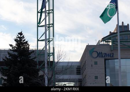 Das Logo der Stadt Ottawa ist am frühen Morgen auf dem Ottawa Rathaus zu sehen, die Flagge von Ottawa vor sich. Stockfoto