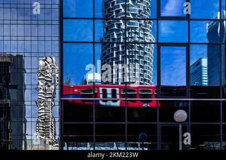 Die Docklands Light Railway spiegelt sich in verspiegelten Glasgebäuden wider, die in der belebten Docklands-Gegend im Osten Londons Büroarbeiter abholen Stockfoto