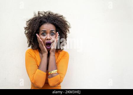 Junge afrikanische Frau mit Händen im Gesicht, während sie vor Ehrfurcht und Furcht schrie, Porträt von Gesichtsausdrücken Stockfoto