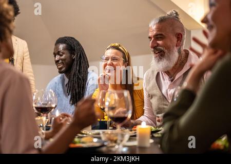 Eine Gruppe von verschiedenen Menschen, die sich Zeit teilen und Spaß beim vegetarischen Abendessen haben, gemischte Freunde, die die Party zu Hause feiern, konzentrieren sich auf kurvige Frauen Stockfoto