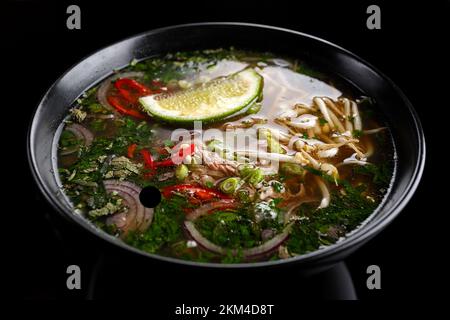 Fo-bo-Suppe aus Rindfleisch mit Gewürzen und Reisnudeln auf schwarzem Hintergrund Stockfoto