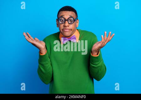 Foto eines lustigen Studenten Akademiker trägt Nerd Brille gleichgültig Keine Ahnung Schulterzucken keine Ahnung wo Buch isoliert auf blauem Hintergrund Stockfoto