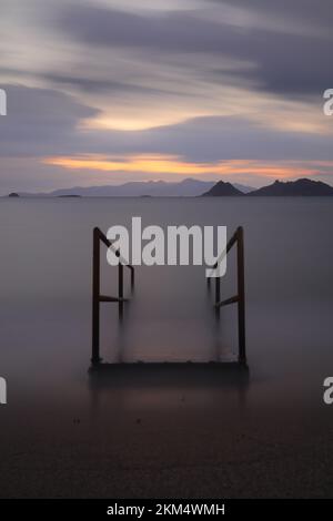 Alte verlassene Holzfischerpier am Meer auf dem Land. Küstenstadt Turgutreis und spektakulärer Sonnenschein. Langzeitbelichtung. Ruhe Stockfoto