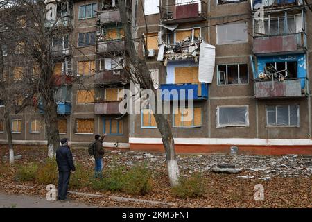 Kramatorsk, Ukraine. 25.. November 2022. Die Leute sehen sich das Wohnungsgebäude an, das durch russische Bomben in Kramatorsk beschädigt wurde. Die ukrainische Energieinfrastruktur wurde diese Woche erneut von Russland angegriffen, wodurch Millionen von Menschen ohne Strom blieben. Während die Temperaturen im ganzen Land unter den Gefrierpunkt fallen, gibt es Befürchtungen, dass Moskau - um den Krieg, den es begonnen hat, zu gewinnen - den Winter "als Waffe" einstuft. Und nirgendwo ist es klarer, wie das aussehen könnte, als in den Städten an der Front im Osten. Kredit: SOPA Images Limited/Alamy Live News Stockfoto