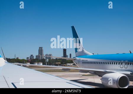 Das Heck eines großen Flugzeugs, das am Tor geparkt ist, mit der Stadt Buenos Aires im Hintergrund. Stockfoto