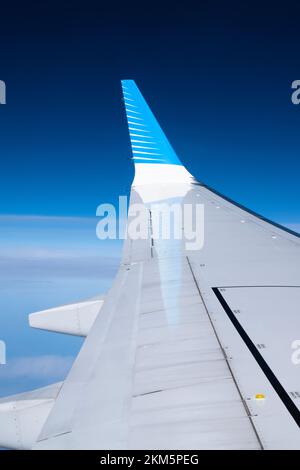 Aus dem Fensterplatz des Flugzeugs zu schauen und die Flügelspitze auf dem Flügel des Flugzeugs zu sehen. Mit tiefblauem Hintergrund. Stockfoto