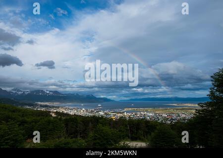 Blick auf die Berge rund um die Stadt Ushuaia. Mit einem Regenbogen über der Stadt an einem Sommertag. Stockfoto