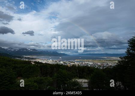 Blick auf die Berge rund um die Stadt Ushuaia. Mit einem Regenbogen über der Stadt an einem Sommertag. Stockfoto