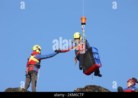 Ballenstedt, Deutschland. 26.. November 2022. Ein Polizeihubschrauber bringt ein Mitglied des Harzer Bergrettungsteams mit einer Winde über dem Bergmassiv auf dem Gegensteinen. Die 20 Mitglieder der Bergwacht, die in der Luftrettung ausgebildet sind, müssen ihre theoretischen Kenntnisse regelmäßig in die Praxis umsetzen. Insgesamt ist dies der vierte Übungstag mit der Polizei. Kredit: Matthias Bein/dpa/Alamy Live News Stockfoto