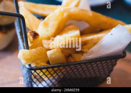 Nahaufnahme eines Metallkorbs gefüllt mit leckeren französischen Kaminen oder gebratenen Kartoffeln. Stockfoto