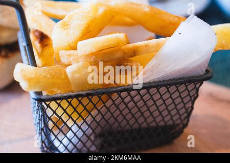 Nahaufnahme eines Metallkorbs gefüllt mit leckeren französischen Kaminen oder gebratenen Kartoffeln. Stockfoto