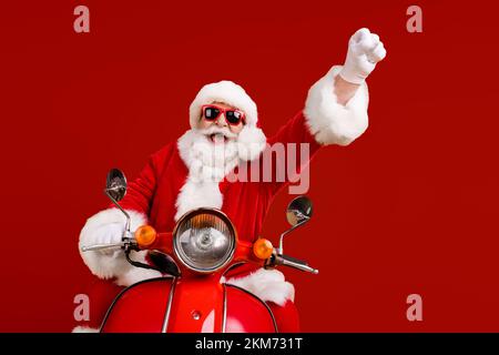 Portrait von seinem er nett lustig fröhlich fröhlichen Santa Reiten Moped schnelle Fahrt mit Spaß steigende Hand nach oben tragen Flauschiges Kostüm isoliert hell Stockfoto