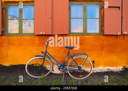 Das Fahrrad lehnt sich gegen die orangefarbene Wand Stockfoto