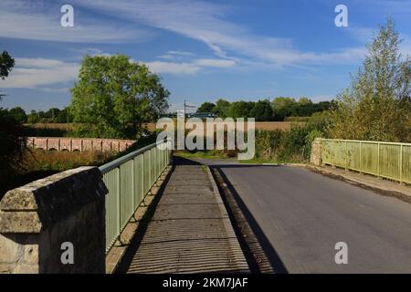 Straßenbrücke über den Fluss Avon in Kellaways, Teil des Maud Heath's Causeway, der sich nach links bewegt, während ein Zug im Hintergrund vorbeifährt. Stockfoto