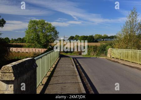 Straßenbrücke über den Fluss Avon in Kellaways, Teil des Maud Heath's Causeway, der sich nach links bewegt, während ein Zug im Hintergrund vorbeifährt. Stockfoto