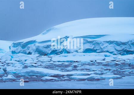 Die Eisfeild und Eisberge, die im Antarktischen Ozean fließen. Mit Schichten aus Eis und Schnee, die die Eisberge bilden. Stockfoto