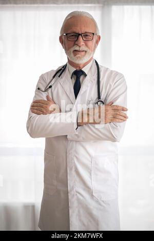 Bild eines selbstbewussten, bärtigen Krankenhausarbeiters, der in der Klinik mit einem Kreuz bewaffnet steht. Stockfoto