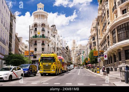 Madrid, Spanien - 20. Juni 2022: Beginn der Gran Via mit Lkw und Verkehr an der Ampel und auf der linken Seite das Grasgebäude, Madrid Stockfoto