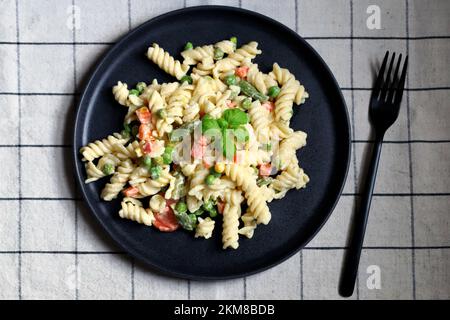 Nudelsalat mit Gemüse mit Sauce und Gewürzen. Stockfoto