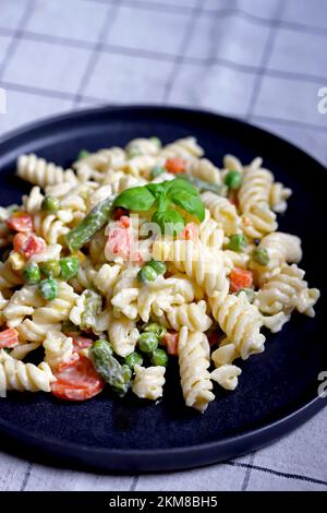 Nudelsalat mit Gemüse mit Sauce und Gewürzen. Stockfoto