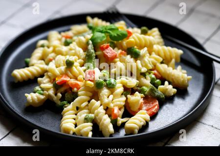 Nudelsalat mit Gemüse mit Sauce und Gewürzen. Stockfoto