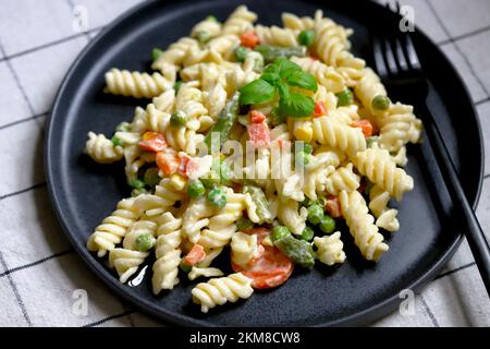 Nudelsalat mit Gemüse mit Sauce und Gewürzen. Stockfoto