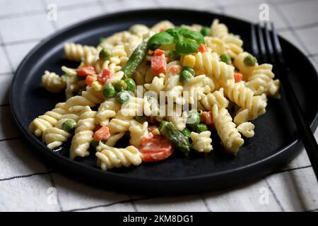 Nudelsalat mit Gemüse mit Sauce und Gewürzen. Stockfoto