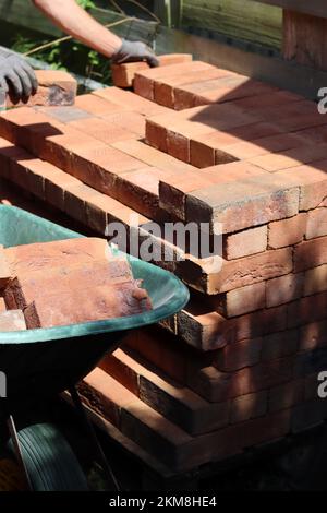 Männerhand mit rotem Ziegel. Bau- und Baukonzept. Hausrenovierung im Gange. Stockfoto