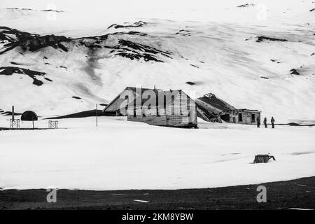 Alte Gebäude auf Deception Island in der Antarktis, Bauteiler bedeckt mit vulkanischem Material und Schnee. Stockfoto