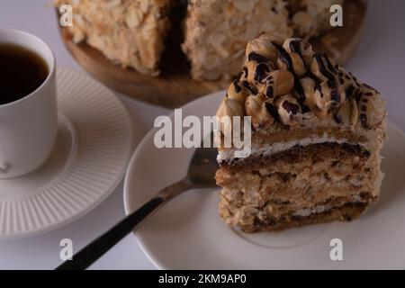 Foto von einem Stück Kuchen und einer Tasse Kaffee neben dem Kuchen auf weißem Hintergrund Stockfoto