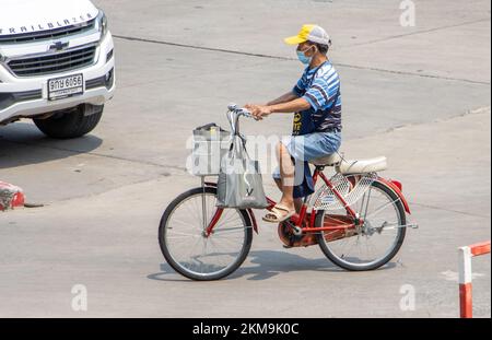 SAMUT PRAKAN, THAILAND, 02 2022. MÄRZ, Ein Mann mit Schürze auf einem Fahrrad auf der City Street. Stockfoto