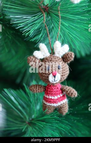 Häkelschmuck als Weihnachtsdekoration auf einem Baum. Süßes Amigurumi-Spielzeug auf einem grünen Weihnachtsbaum. Stockfoto