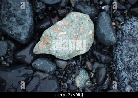Nahaufnahme eines bunten Felsens zwischen dunklen Felsen an einem Strand in der Antarktis. Stockfoto