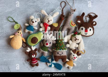 Weihnachtsgehäkelte. Süßes Häkelspielzeug Foto von oben. Wunderschöne Amigurumi-Tiere. Hausgemachte Weihnachtsgeschenke. Grauer Hintergrund mit Kopierbereich. Stockfoto