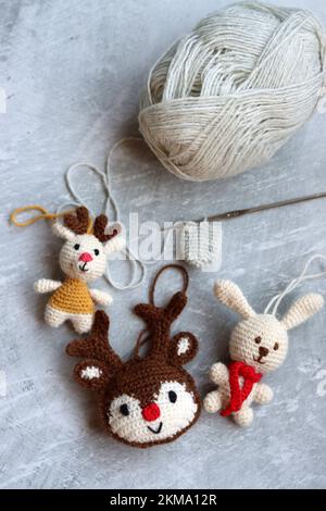 Weihnachtsgehäkelte. Süßes Häkelspielzeug Foto von oben. Wunderschöne Amigurumi-Tiere. Hausgemachte Weihnachtsgeschenke. Grauer Hintergrund mit Kopierbereich. Stockfoto