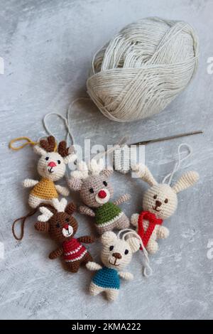 Weihnachtsgehäkelte. Süßes Häkelspielzeug Foto von oben. Wunderschöne Amigurumi-Tiere. Hausgemachte Weihnachtsgeschenke. Grauer Hintergrund mit Kopierbereich. Stockfoto