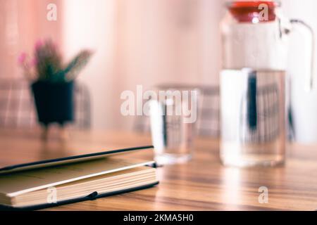 Farbmuster in Pastelltönen, Notizbuch auf Holztisch und eine Kanne Wasser, glass.selective Fokus. Stockfoto