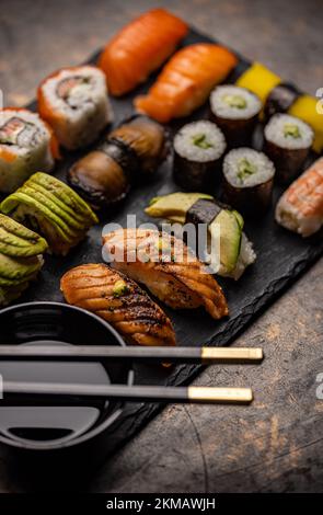 Verschiedene Sushi-Sorten. Sushi auf Schiefer serviert mit Soja Stockfoto